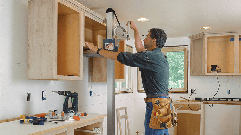 Contractor measuring cabinet height in a new kitchen installation