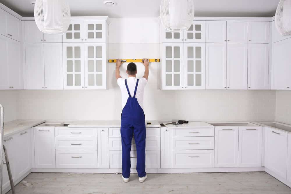 Contractor measuring for precise installation of kitchen cabinets