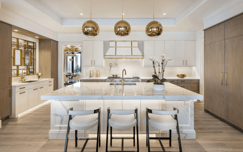 Boutique hotel kitchen featuring sleek painted white cabinets with gold hardware