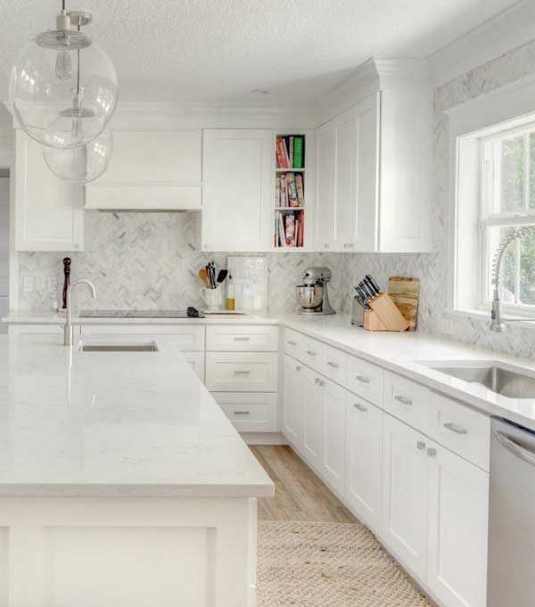 Bright kitchen with white painted cabinets, marble countertops, and large windows