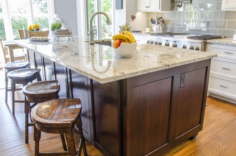 Kitchen island with dark wood base and light stone countertop for bold contrast