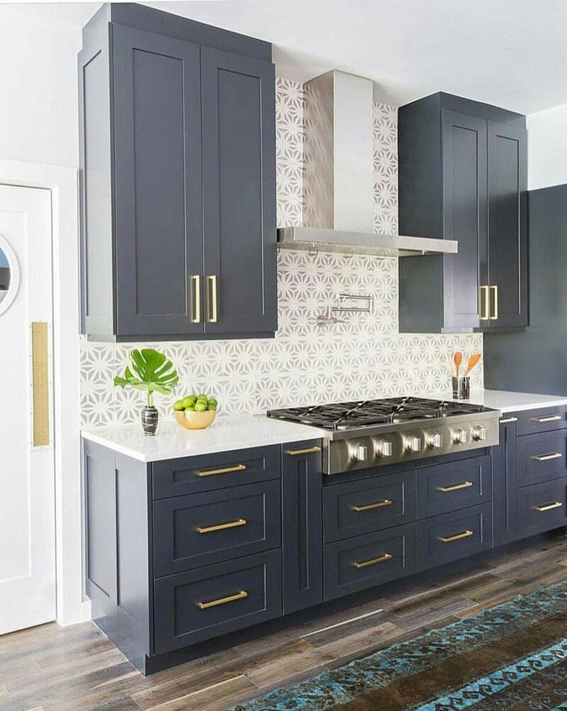 Modern kitchen featuring a combination of navy blue painted cabinets and white upper cabinets with gold hardware