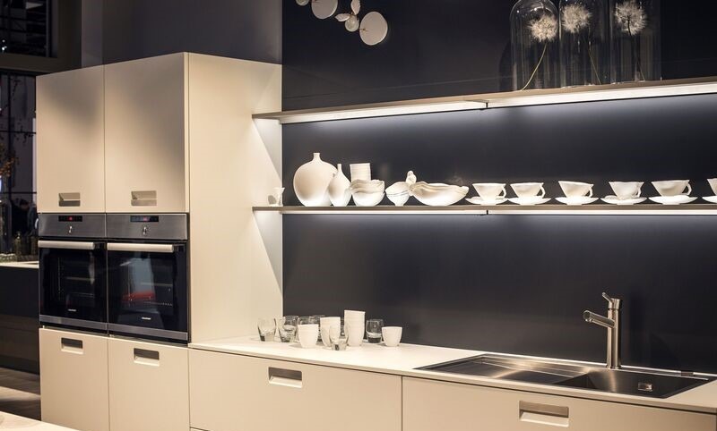 Modern kitchen featuring backlit open shelves showcasing decorative glassware and ceramics