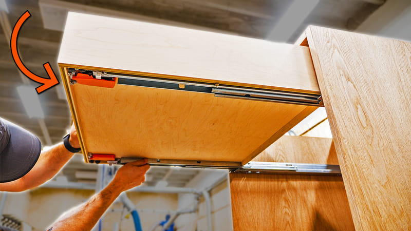 A close-up of a carpenter aligning drawer slides for a smooth fit during cabinet installation