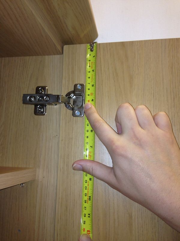 A contractor carefully measuring a cabinet door for proper pull placement