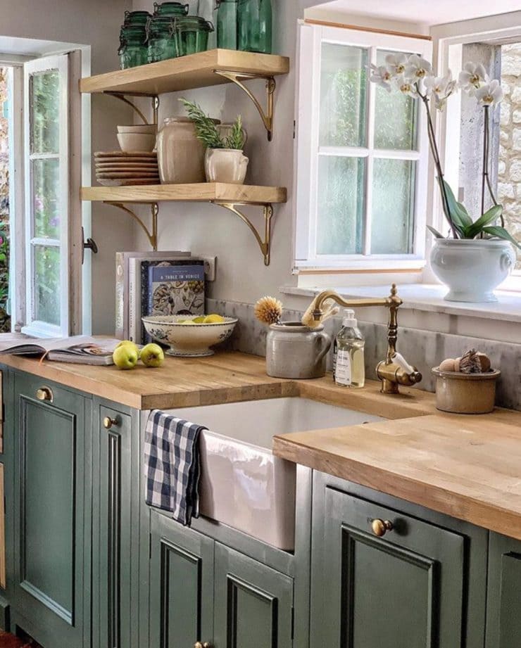 A rustic kitchen with forest green painted cabinets and oak wood countertops, offering a cozy and earthy ambiance