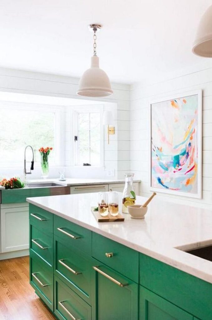 A luxurious kitchen featuring emerald green painted cabinets, complemented by white marble countertops and brass hardware for a sophisticated look