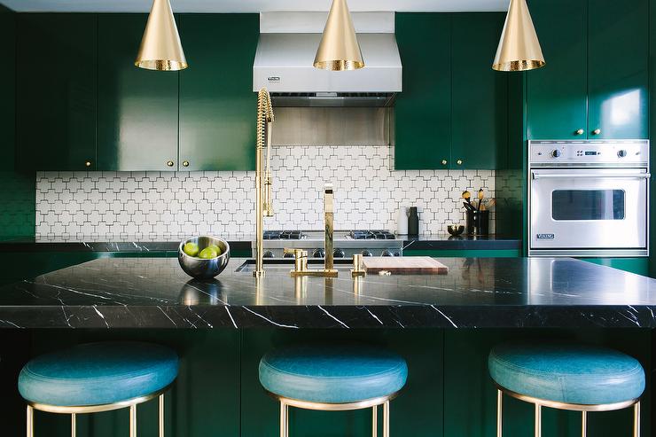 A luxurious emerald green kitchen with coordinated dark marble countertops