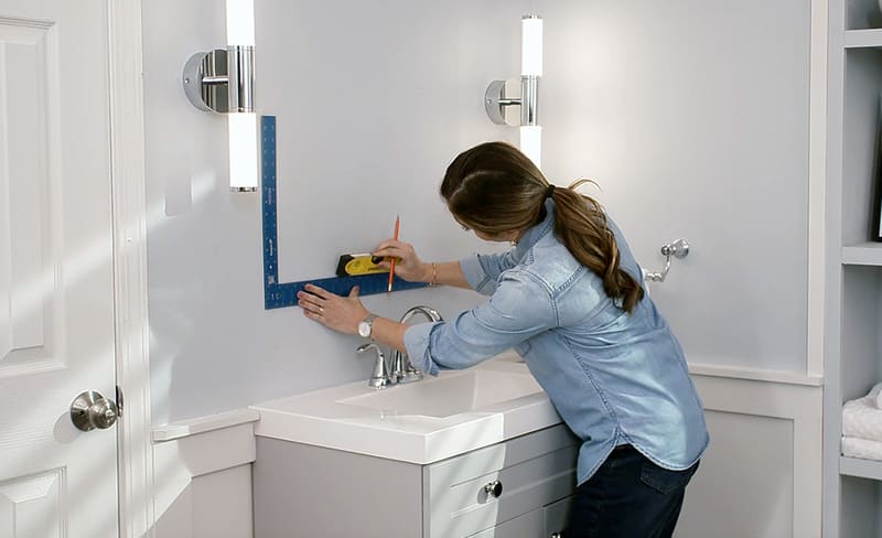 A contractor installing a long recessed medicine cabinet with a sleek, modern design in a bright bathroom