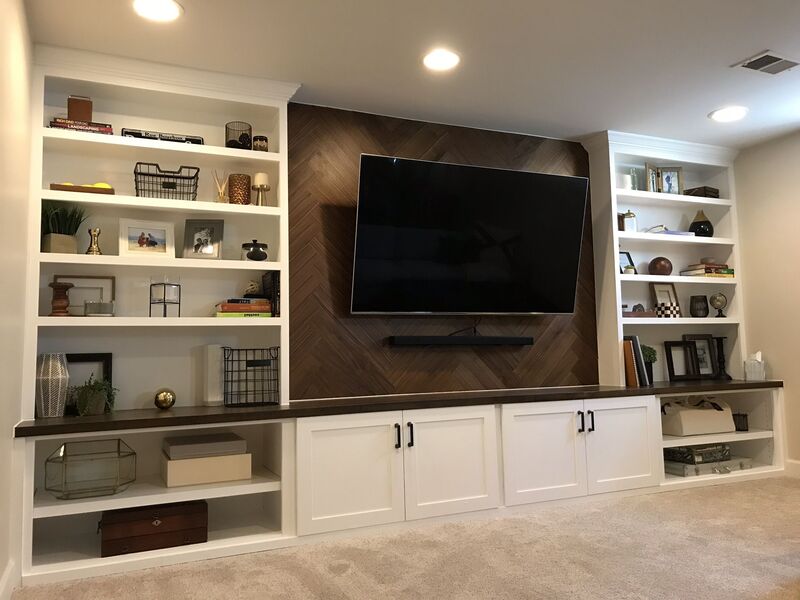 A wide custom media cabinet with built-in shelves flanking a large-screen TV in a luxurious home