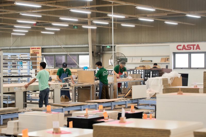 Skilled workers assembling a custom media cabinet in a state-of-the-art manufacturing facility