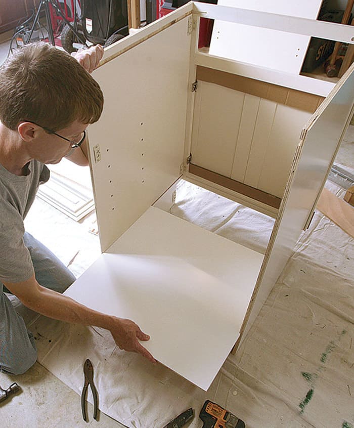 A contractor assembling white Slim Shaker RTA cabinets in a contemporary kitchen, demonstrating ease of installation