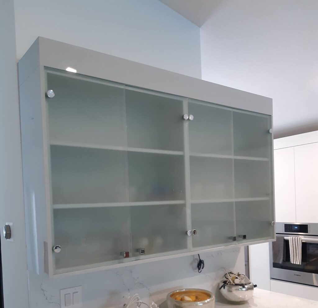 Handle-free push-to-open glass front cabinet door in white lacquer