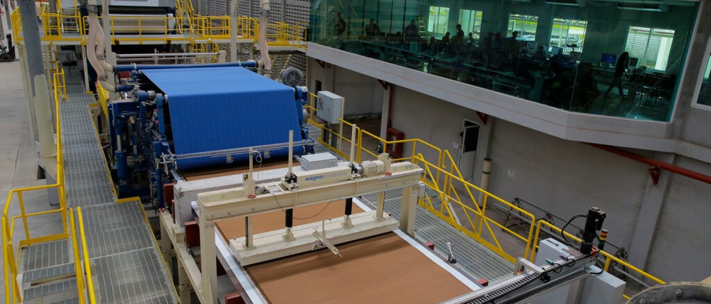 Production line showing high-pressure pressing of hardboard panels under heat
