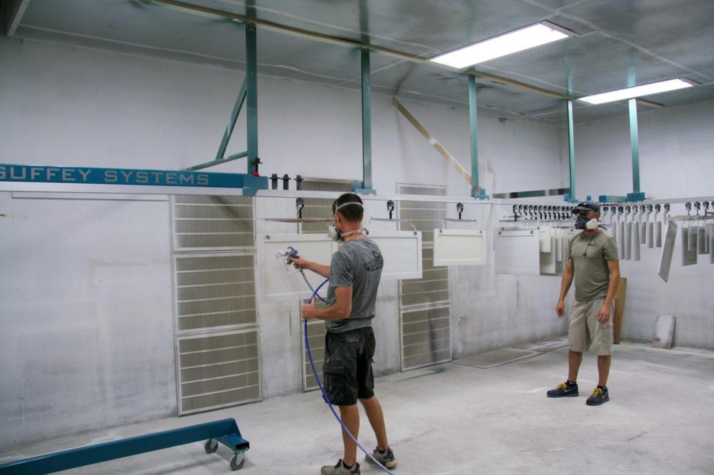 Factory spray booth applying finish to cabinet doors