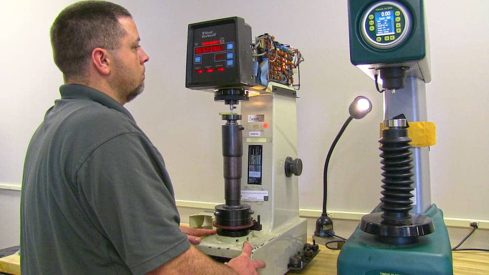 Technician testing cabinet finish hardness in a lab setting