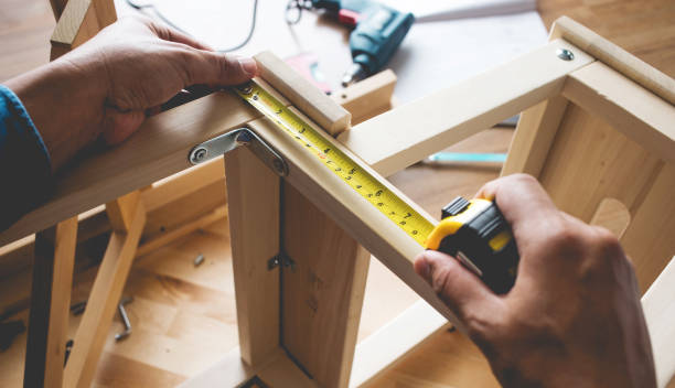 Factory worker measuring a cabinet panel with a tape measure