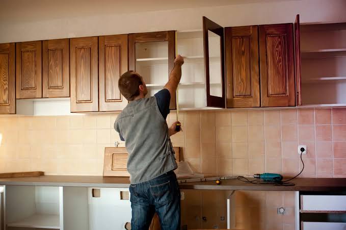 Installer fitting a wall cabinet in a new kitchen